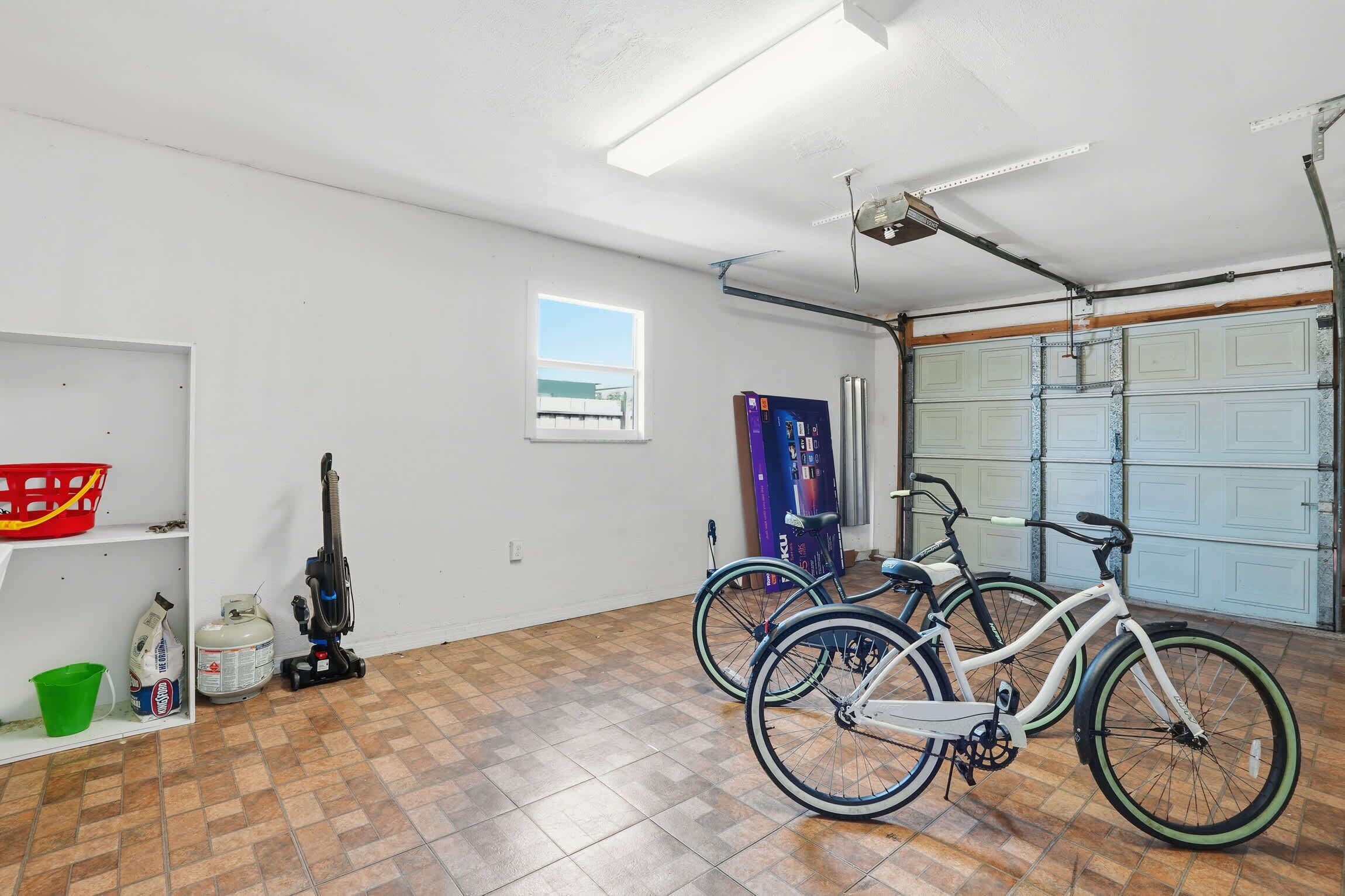 A garage with two bicycles, a vacuum cleaner, and a window.