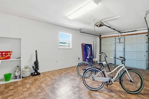 A garage with two bicycles, a vacuum cleaner, and a window.