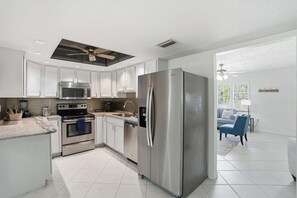 A modern kitchen with stainless steel appliances, white cabinetry, and a central island.