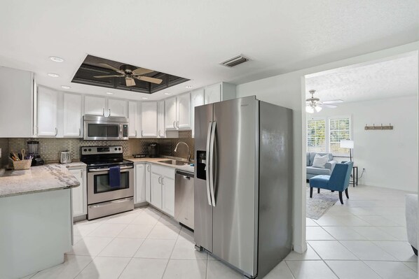 A modern kitchen with stainless steel appliances, white cabinetry, and a central island.