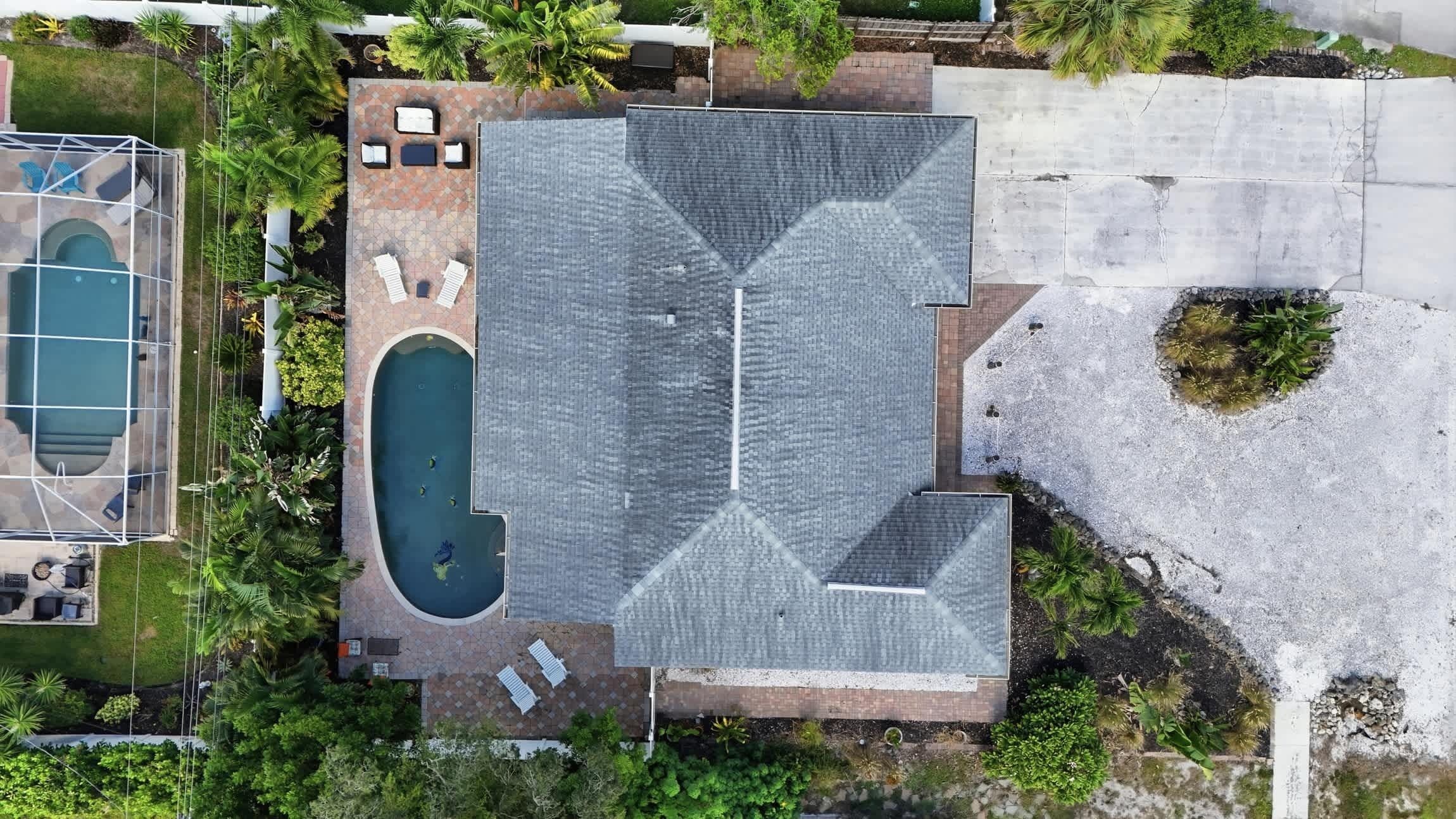 Ovenudblik over en boligejendom med swimmingpool, overdækket terrasse og et stort tagdækket område.