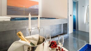 A modern bathroom with a large bathtub, a painting of a sunset, and a champagne bottle on the counter.