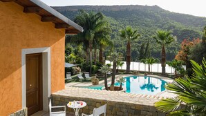 A pool area with a stone wall, two white chairs, and a wooden door.