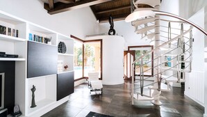 A modern interior with a spiral staircase, a fireplace, and a bookshelf.