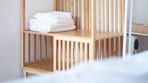 Un armadio in legno con ripiani multipli e un'asta appendiabiti, contenente asciugamani bianchi piegati.