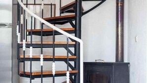 Una scala a chiocciola con gradini in legno e ringhiere in metallo nero, che conduce a un piano superiore.