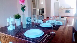 Een eethoek met een tafel voor twee personen, een bloevas en een keuken op de achtergrond.