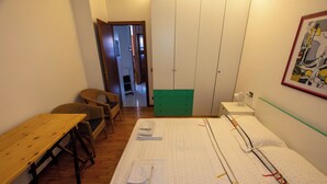 Une pièce comprenant un lit, une table en bois, une chaise en osier et une armoire verte.