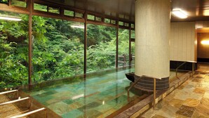 Un espace bien-être comprenant un jacuzzi à ciel ouvert, une terrasse en bois et une vue sur une végétation luxuriante.