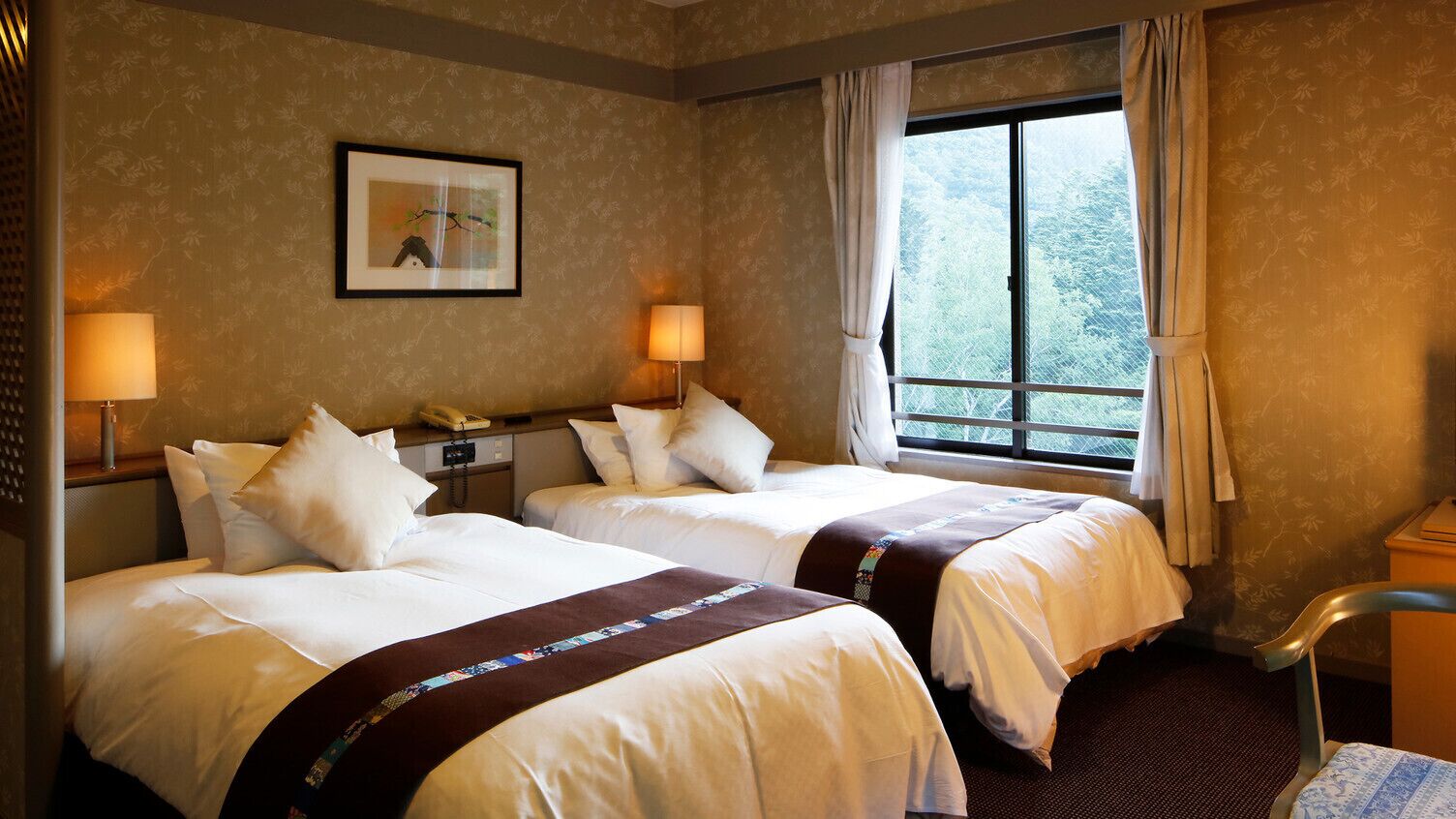 Une chambre d’hôtel avec deux lits, un bureau, une chaise, une fenêtre avec des rideaux et un tableau encadré au mur.
