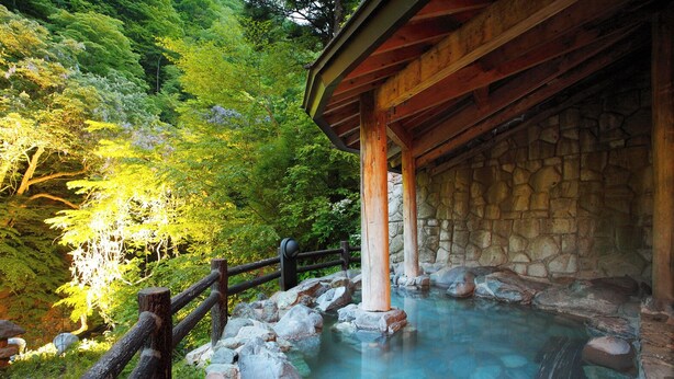 Un onsen japonais traditionnel, avec une structure en bois et des murs en pierre.
