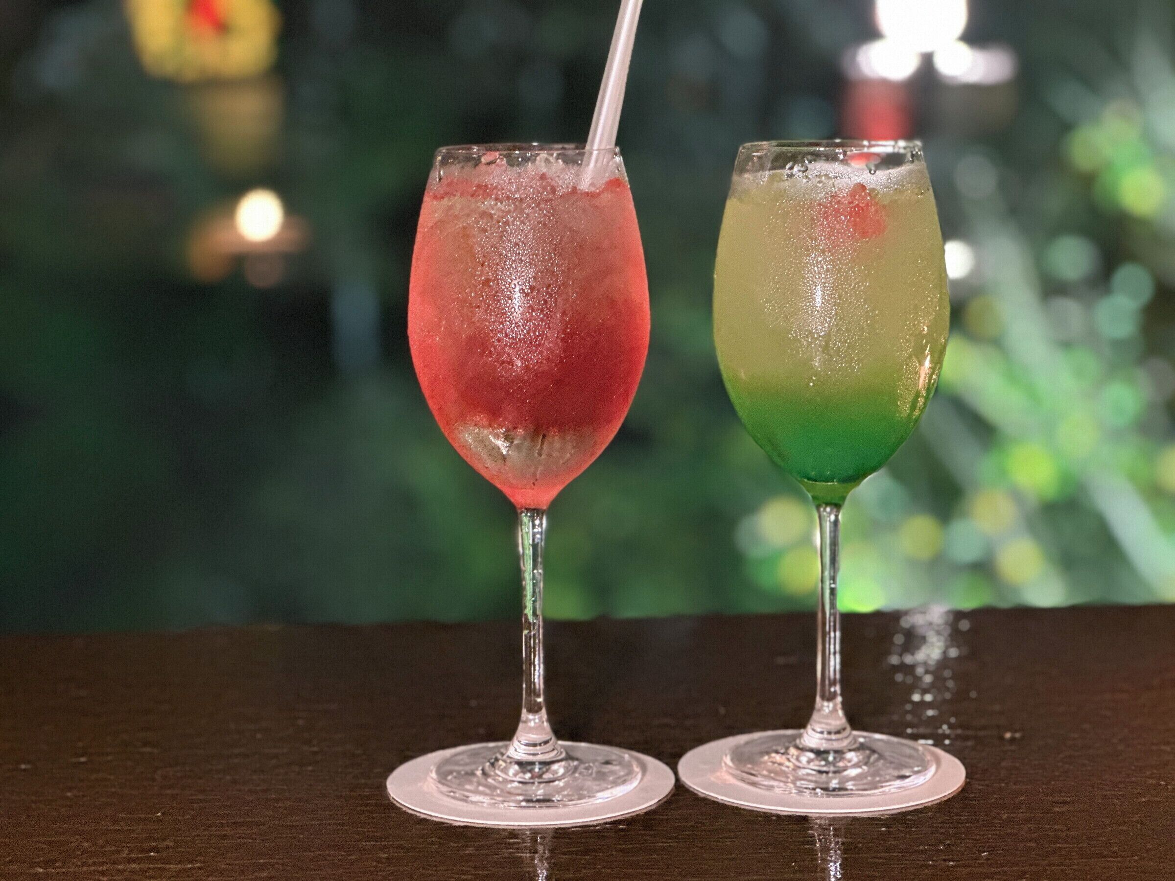 Zwei Cocktails auf einem Holztisch, unscharfer Hintergrund.