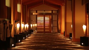 Un bâtiment traditionnel japonais, avec une entrée en bois et des lanternes disposées le long du chemin.