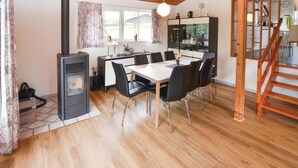A dining area with a wooden table and chairs, a built-in stove, and a kitchen area with cabinets and a mirror. - 2 bedroom pet friendly home in Broager (Broager)