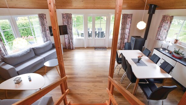 A spacious living area with a wooden ceiling, a sofa, a dining table with chairs, and large windows with curtains. - 2 bedroom pet friendly home in Broager (Broager)