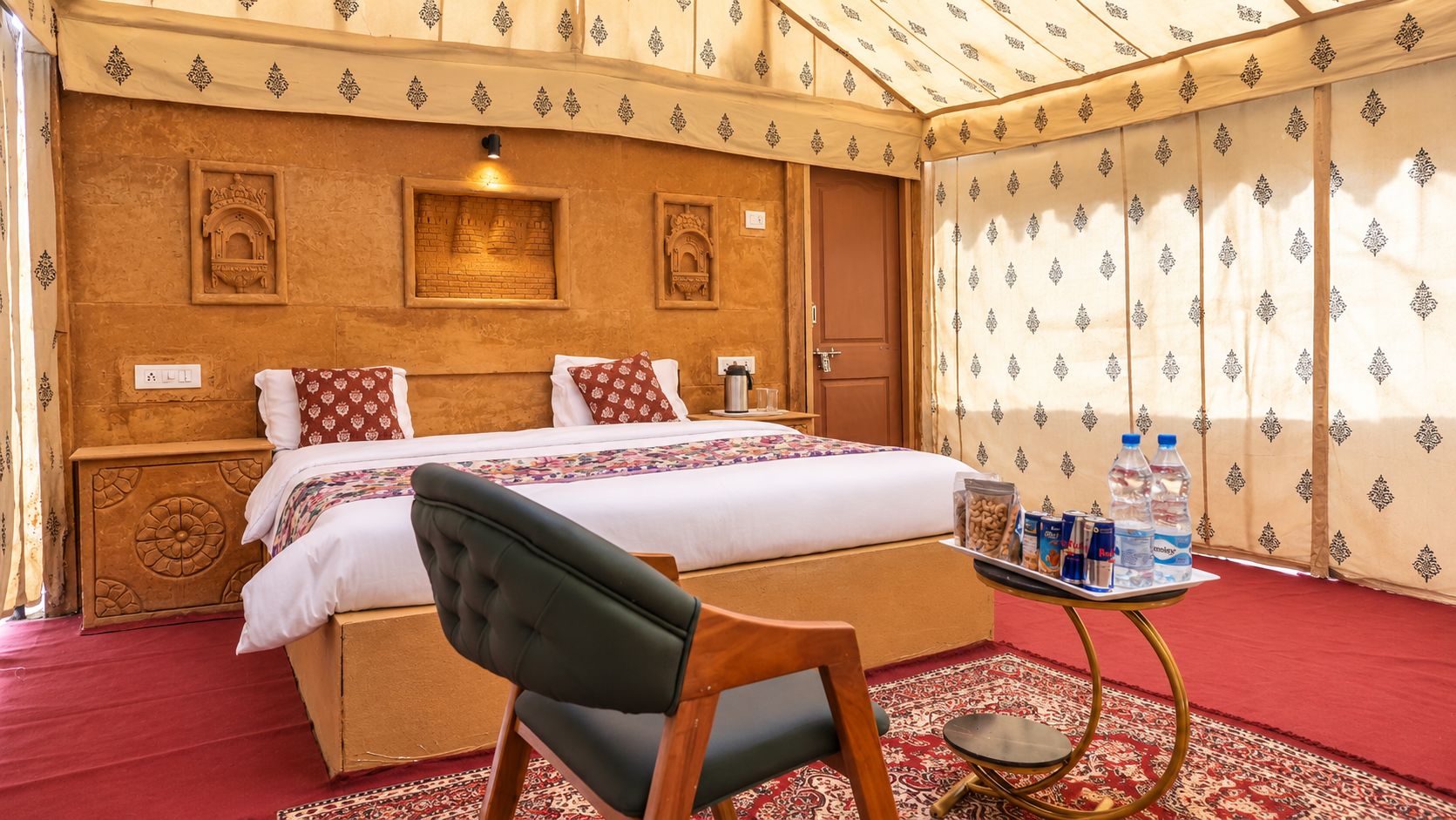 Une chambre d'hôtel avec un lit, une chaise, une petite table avec des bouteilles d'eau et un mur décoré de motifs.