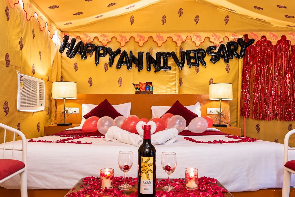 Ein Zimmer, festlich für ein Hochzeitjubiläum dekoriert, mit einem Bett, Luftballons und Rosenblättern.