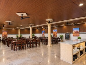 A spacious restaurant with multiple tables and chairs, ceiling fans, and a marble floor.