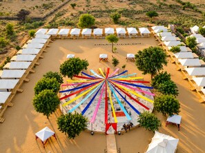A circular outdoor seating area with a central fountain, surrounded by tents and trees.