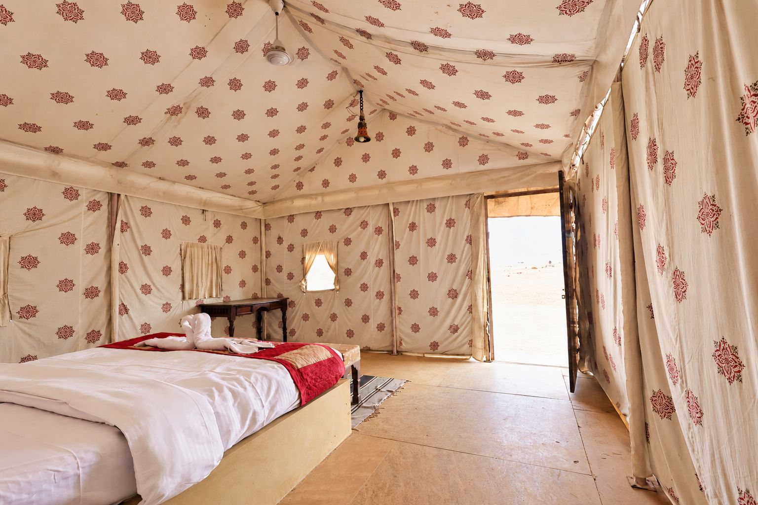 A tent-style room with a bed, a small table, and curtains.