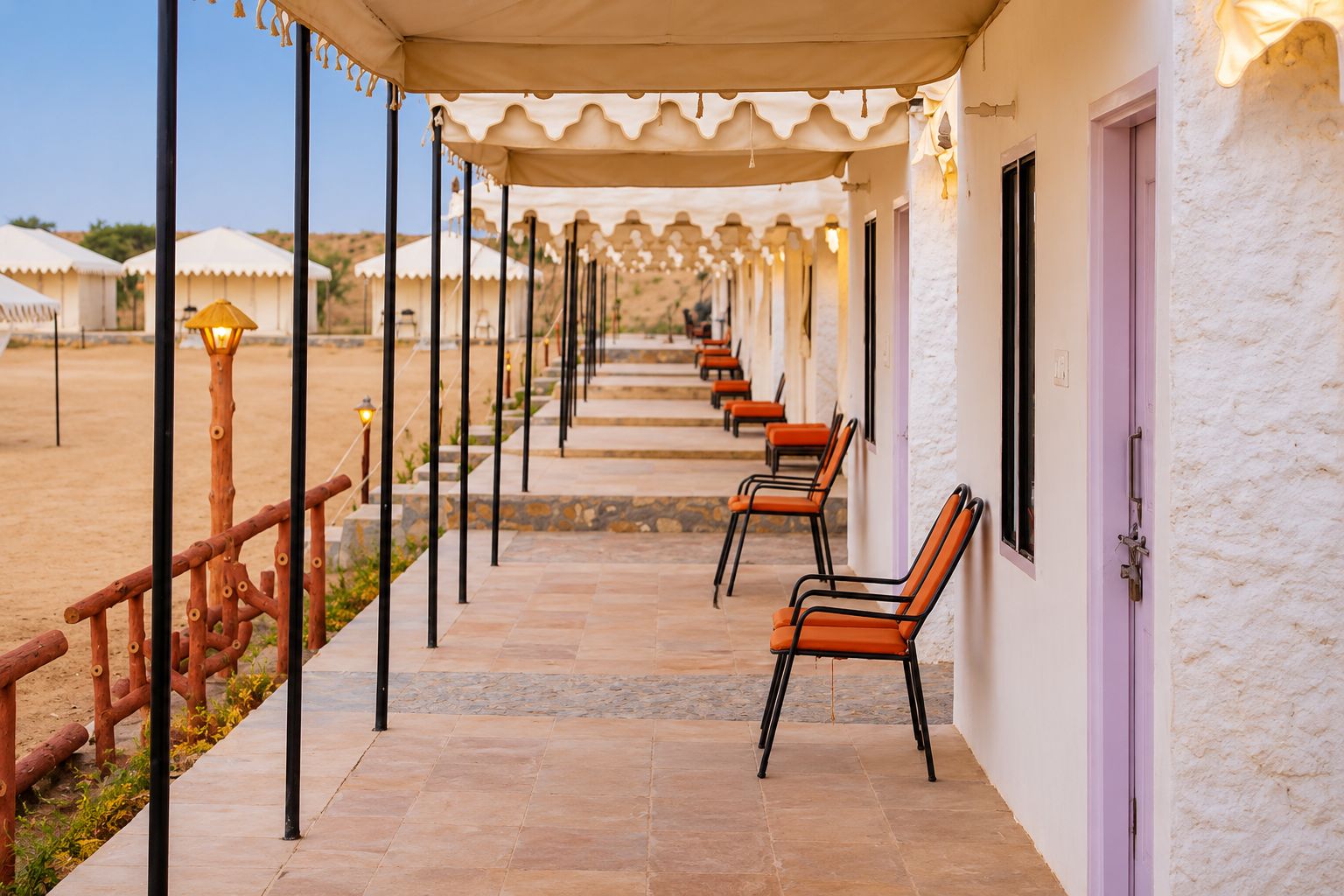 A covered outdoor seating area with chairs and a railing, leading to a building with a door.