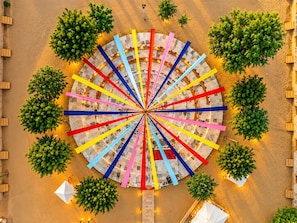 A circular outdoor seating area with multiple tables and chairs, surrounded by trees.