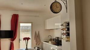 Eine Küche mit einer Uhr, roten Vorhängen, einem Fernseher und einem Fenster mit Aussicht.