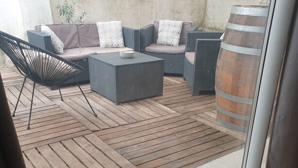 Eine Terrasse mit Gartenmöbeln, Holzboden und einem großen Fass.