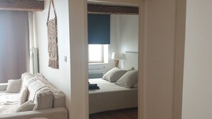 Ein Zimmer mit Bett, Stuhl, Tisch und Fenster.