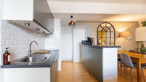 A modern kitchen with a built-in island, a dining area with a wooden table and chairs, and a pendant light above the island.