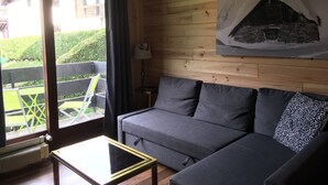 A modern living room with a grey sofa, a small table, and a painting of a snowy mountain on the wall. - Apartment 4/6 pers, 50m², Les Houches Chamonix (Les Houches)