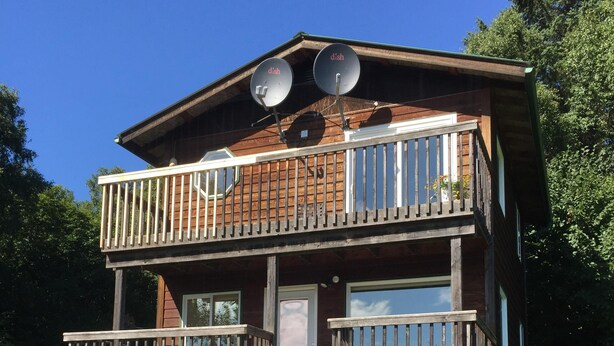 A two-story wooden cabin with a balcony, a staircase, and a small deck area. -  Fern Creek
Convenient location w/ spectacular views! (Homer)