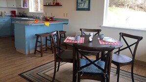 A kitchen with a blue island, wooden chairs, and a dining table set for four. -  Fern Creek
Convenient location w/ spectacular views! (Homer)