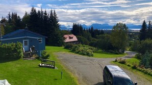A residential area with a blue house, a red-roofed building, and a white van parked on a dirt road. -  Fern Creek
Convenient location w/ spectacular views! (Homer)