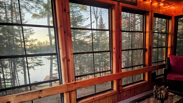 A cabin with large windows offering views of a forest and a lake. - Lake Days, Bonfires
& Cabin Nights
2 Bedrooms / 2 Bathrooms  (Boulder Junction)