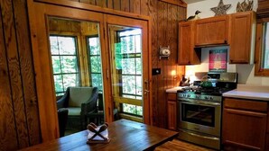A wooden interior with a kitchen area, including a stove, cabinets, and a dining table with a bench. - Lake Days, Bonfires
& Cabin Nights
2 Bedrooms / 2 Bathrooms  (Boulder Junction)
