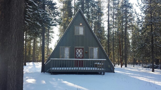 A cabin with a triangular roof, a porch, and a door with a window above it.