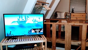 A television on a wooden stand in a room with a sloped ceiling and a small wooden table.