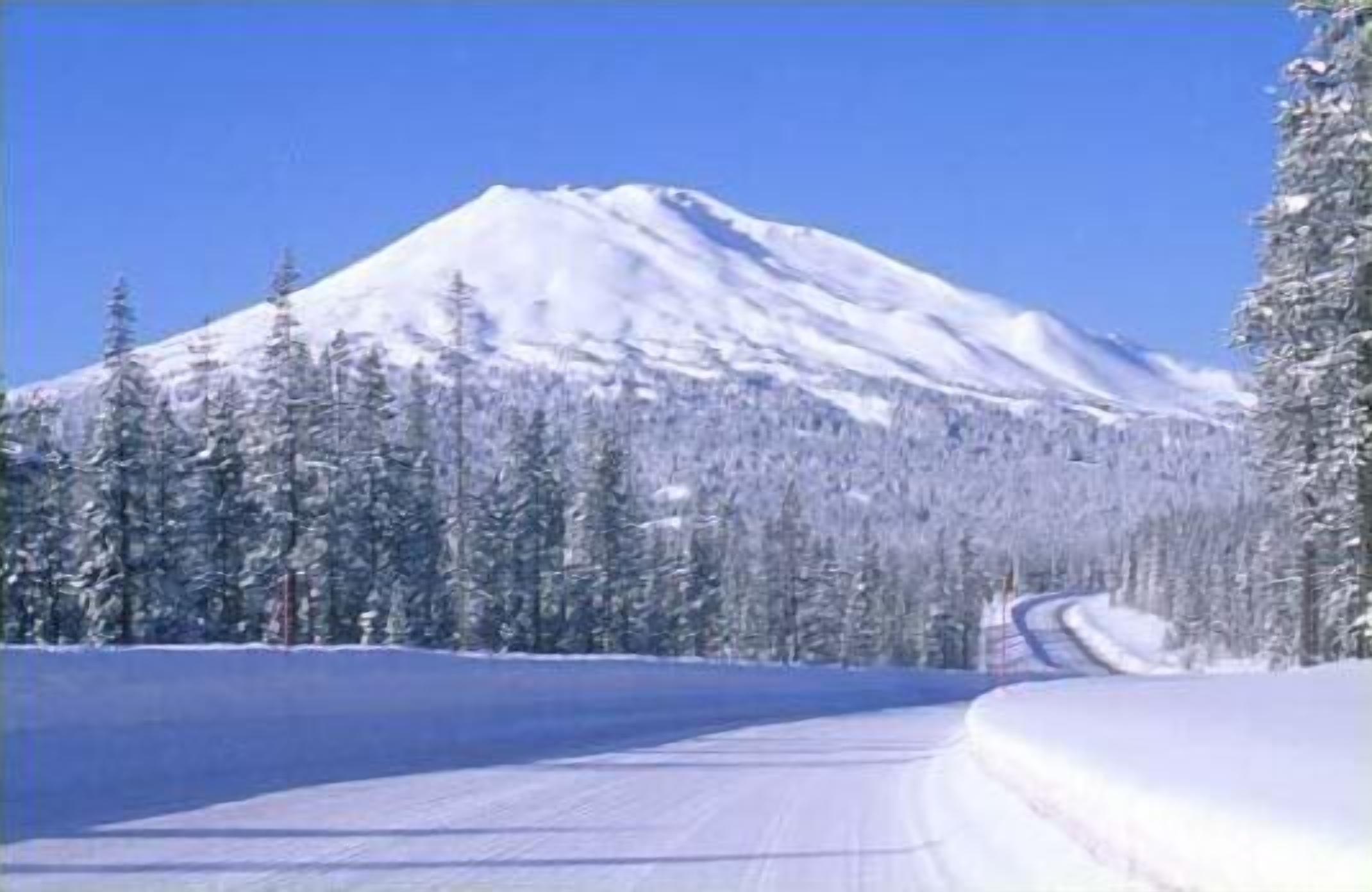A snow-covered mountain road with a clear sky.