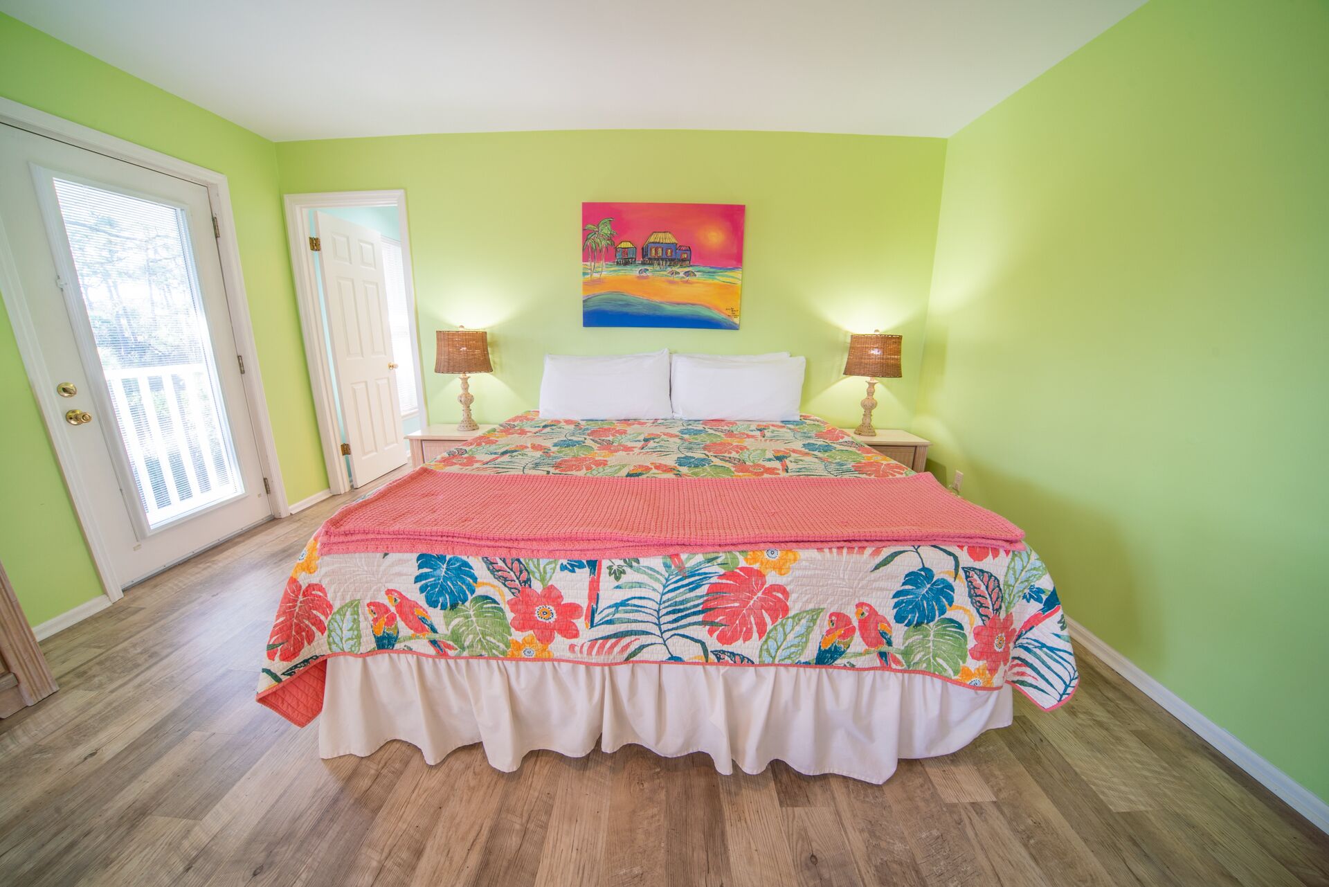 Une chambre à coucher avec un lit, deux lampes de chevet, un tableau et une porte.