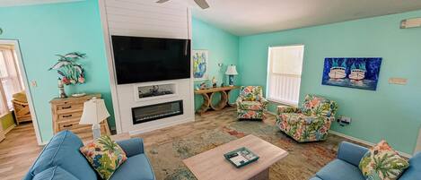A living room with a TV, two sofas, a coffee table, and a ceiling fan.