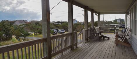 A wooden deck with outdoor seating and a view of a residential area.