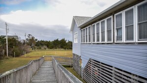 En träpromenad leder fram till en byggnad med flera fönster.
