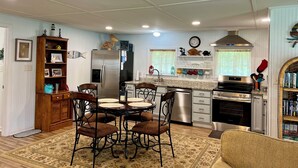 A modern kitchen with a central island, stainless steel appliances, and a dining area with a round table and chairs.