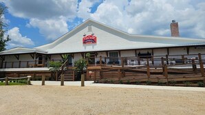 A TINTOP Restaurant with a white exterior, a covered outdoor seating area, and a fenced-in horse riding arena.