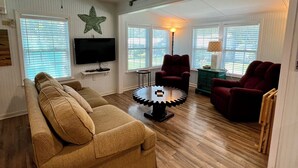 A living room with a sofa, armchairs, a coffee table, and a television.