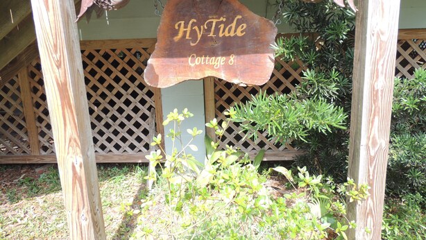 A wooden sign with the text "Hy Tide Cottage 8" hanging above a wooden structure.