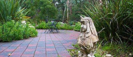 A garden with a statue, a paved path, and various plants.