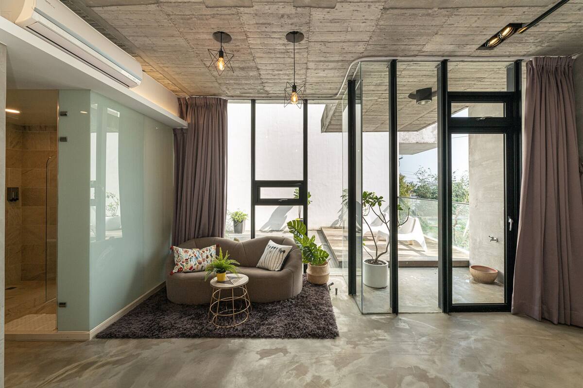 A modern living room with a sofa, a coffee table, and potted plants.