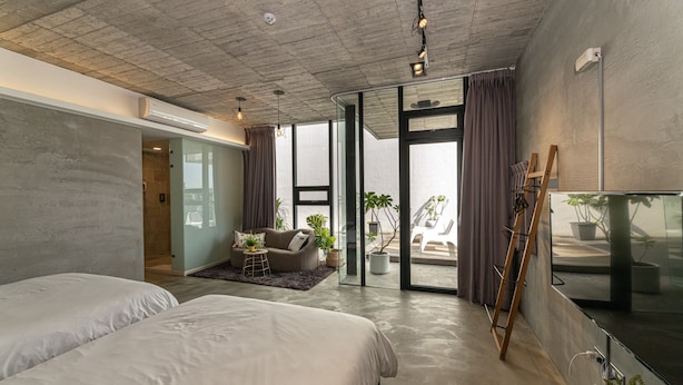 A modern hotel room with a large bed, a sofa, a small table, and a balcony with plants. - Aloe Villa (Wujie)